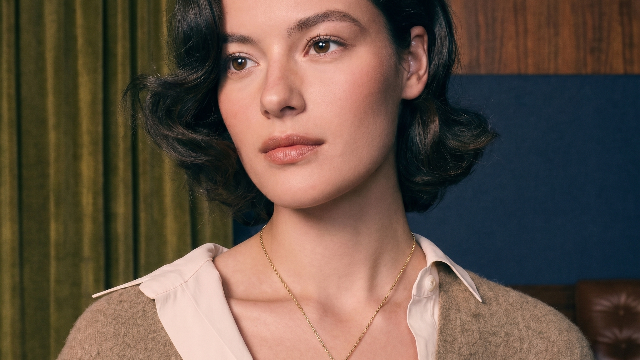 Diamond charm necklace layered on a woman's decolletage in solid gold, soft natural light