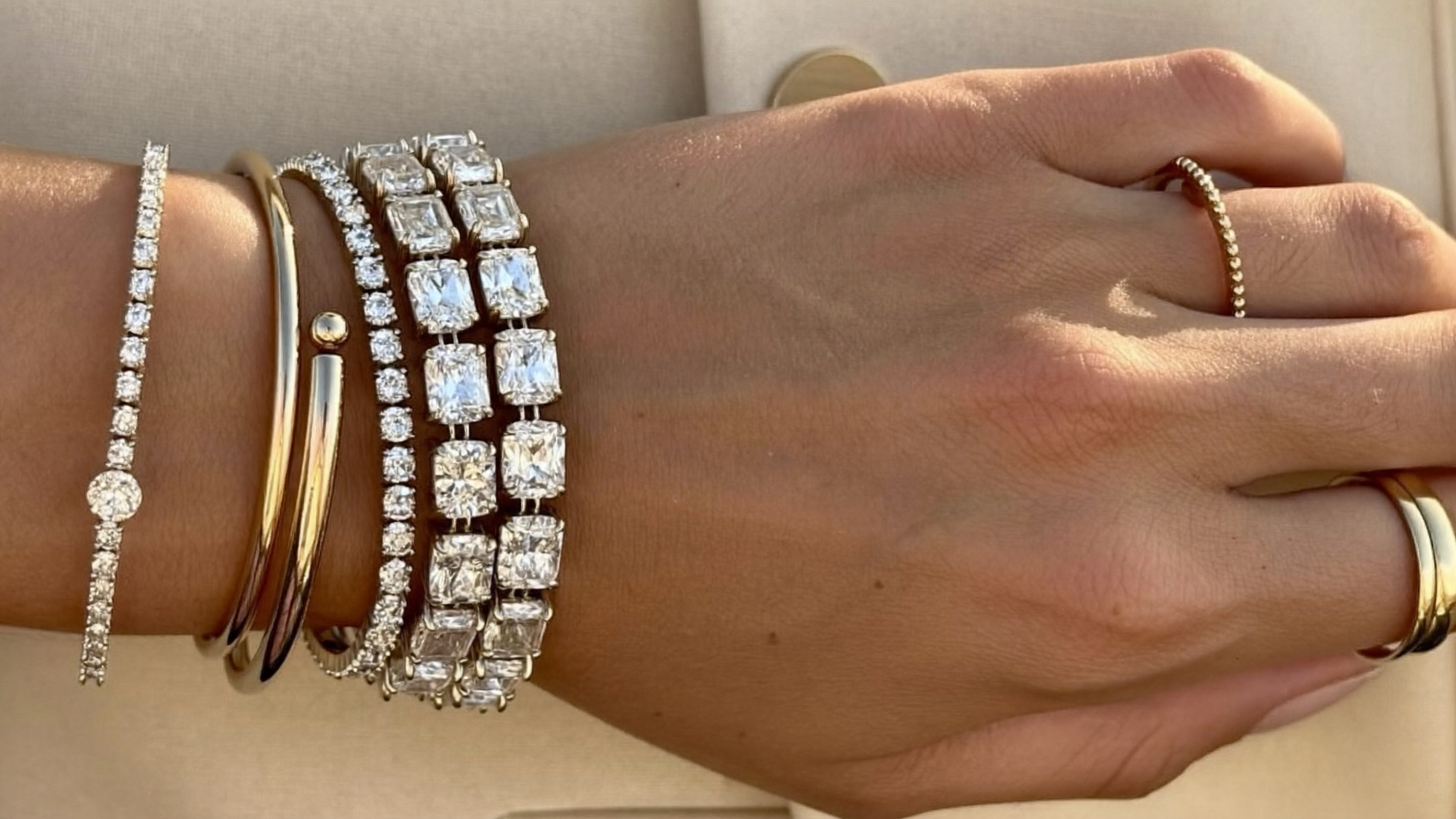 Stacked lab-grown diamond tennis bracelets in solid gold layered on a woman's wrist
