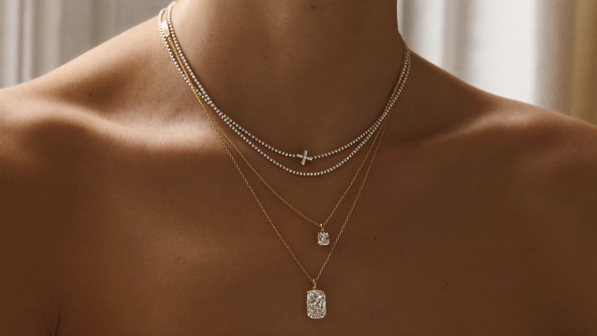 Layered diamond necklaces at varying lengths in solid gold on a neckline, showing how to layer necklaces, in natural light