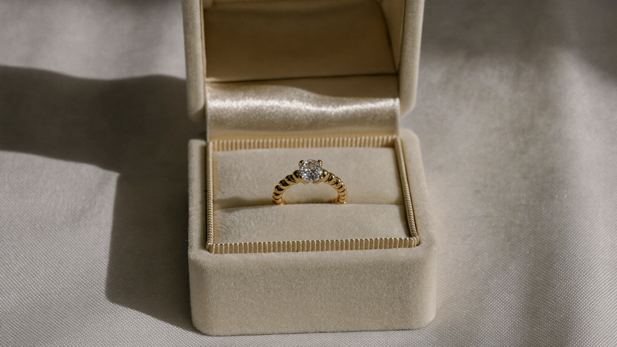 Gold lab grown diamond engagement ring in an open velvet box on linen, engagement ring insurance guide