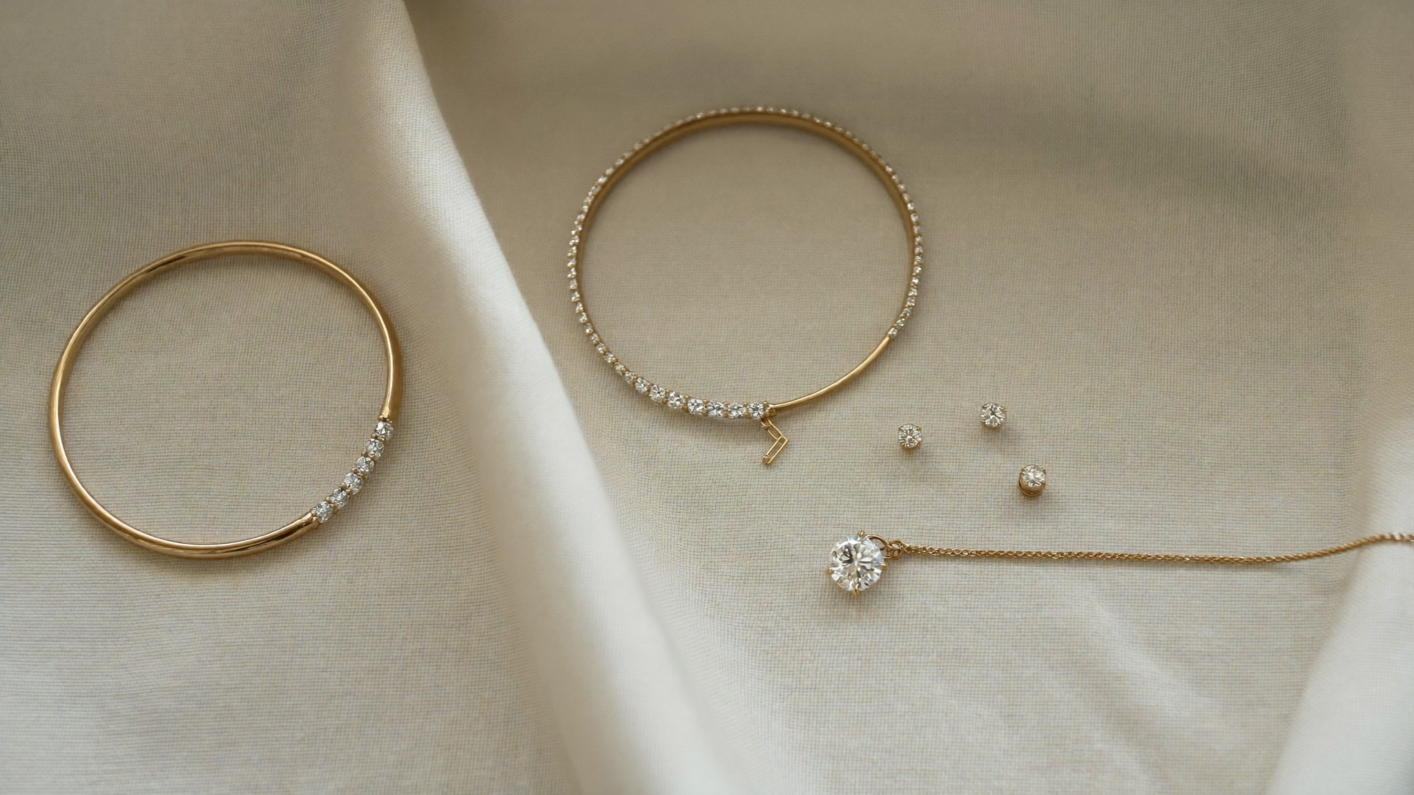 Flat lay of fine jewelry essentials in solid gold with lab grown diamonds on cream linen
