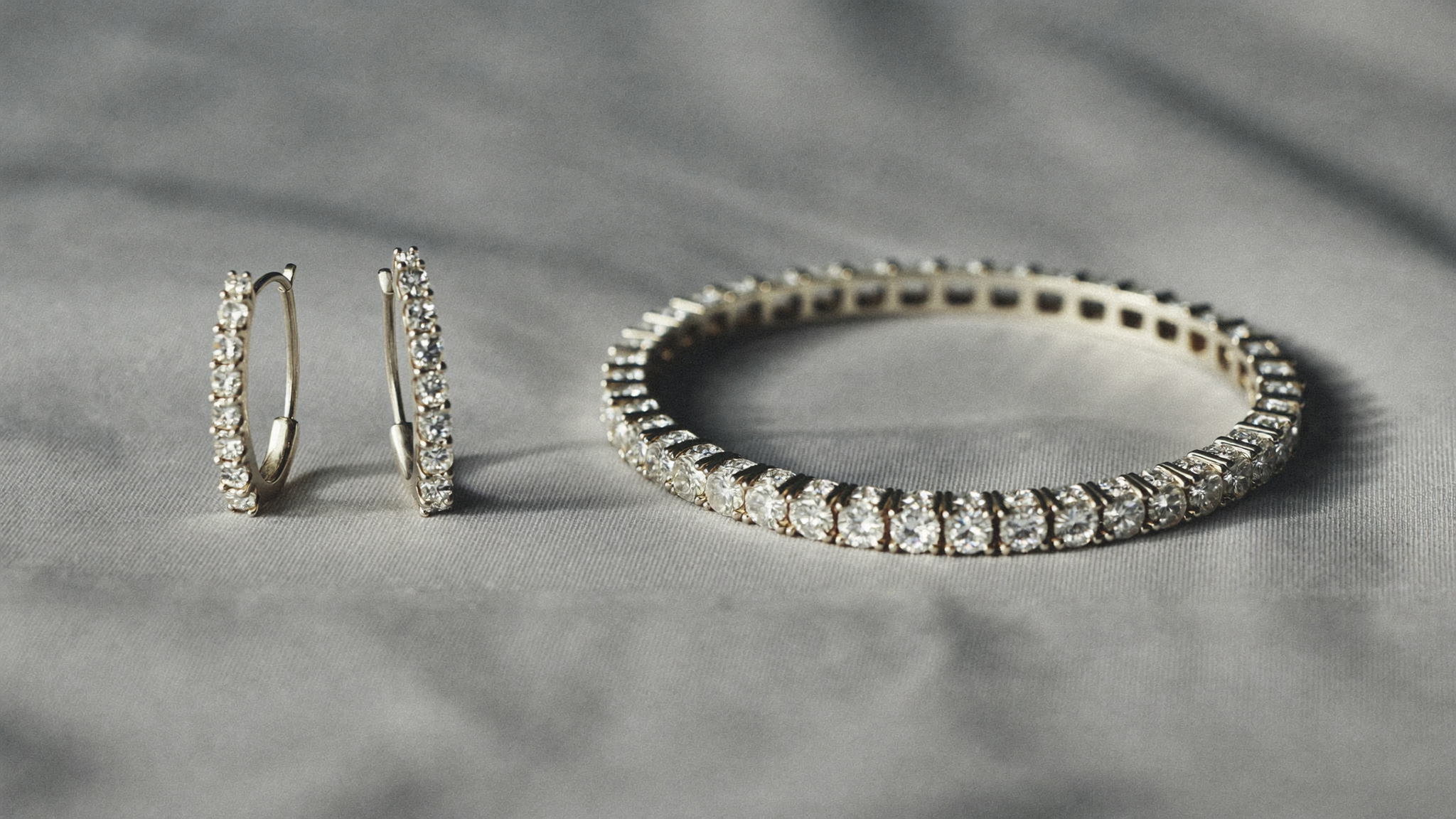 White gold lab grown diamond hoop earrings and tennis bracelet on pale grey silk, white gold jewelry trend 2026