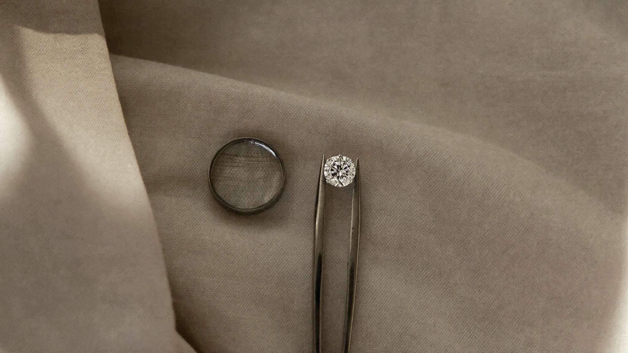 IGI vs GIA lab grown diamond grading: a loose round brilliant lab grown diamond held in tweezers beside a jewellers loupe on linen