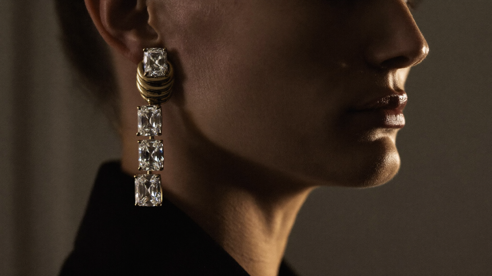 Diamond drop earrings in solid gold worn in profile under warm low evening light