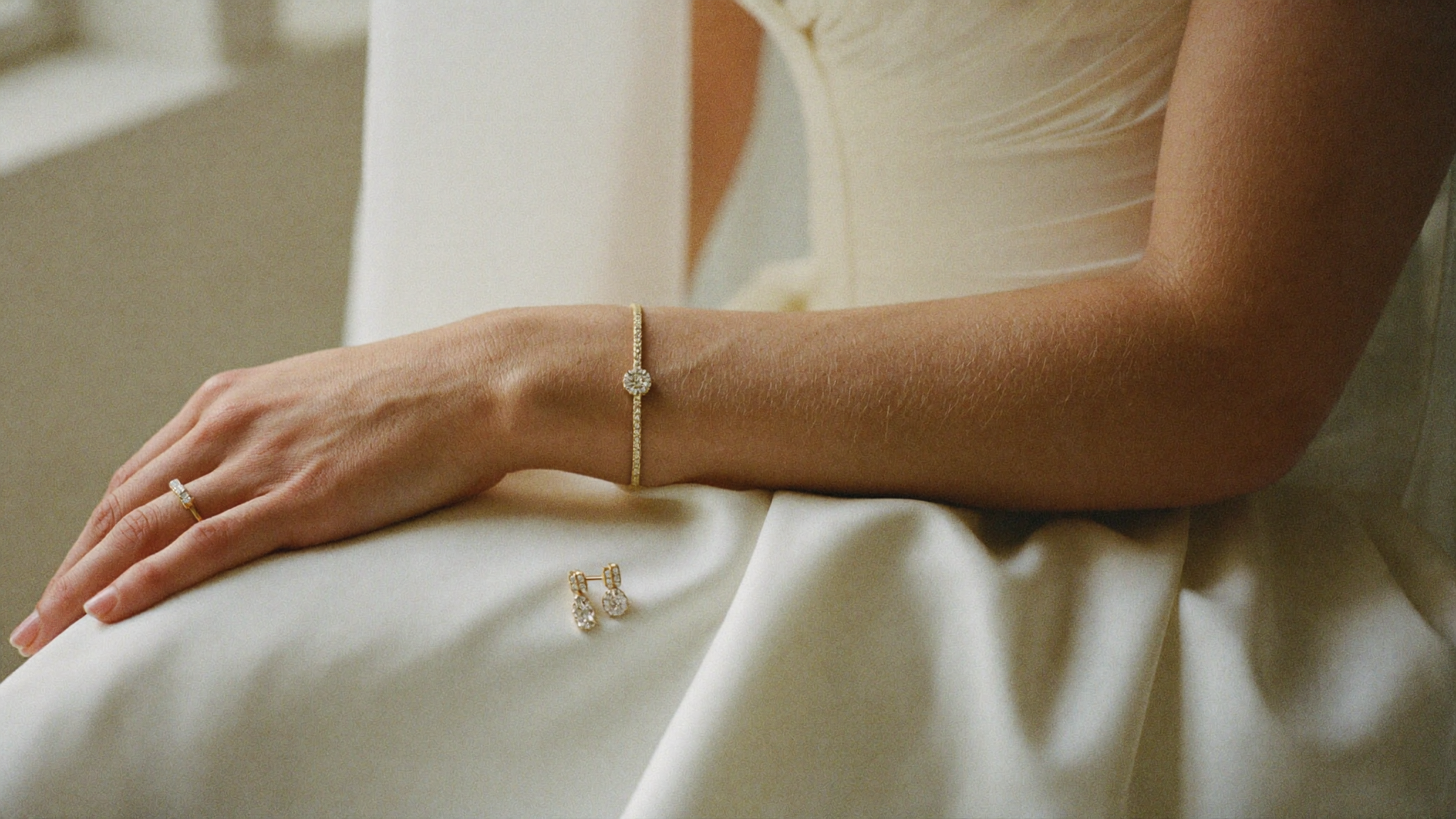 Bride wearing a diamond tennis bracelet and gold band on ivory silk, bridal jewelry styling